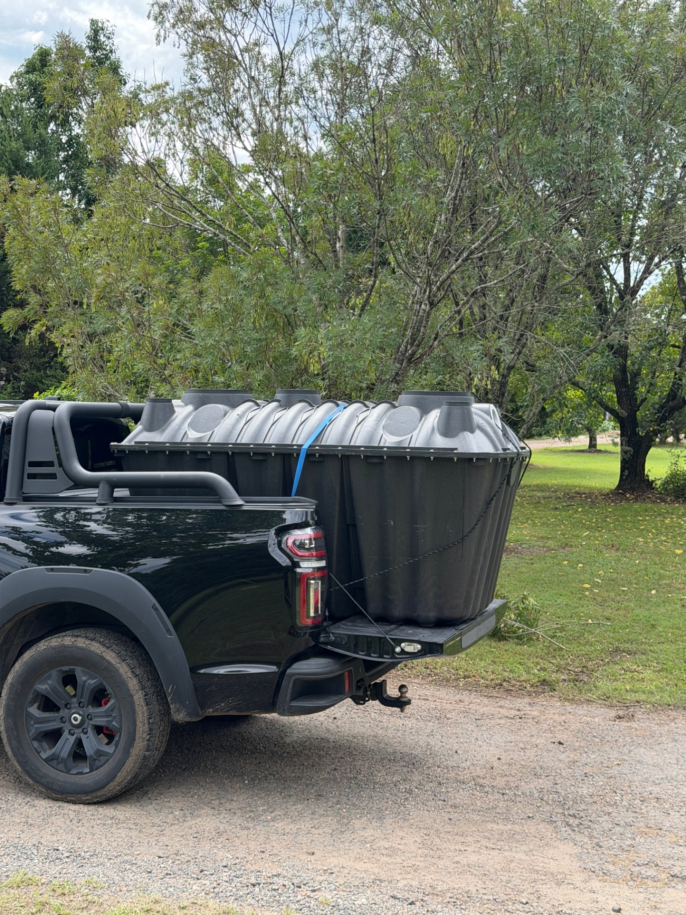 1500L Bush Billabongs septic tank strapped onto the tray of a black ute, ready for transport to a regional Australian property