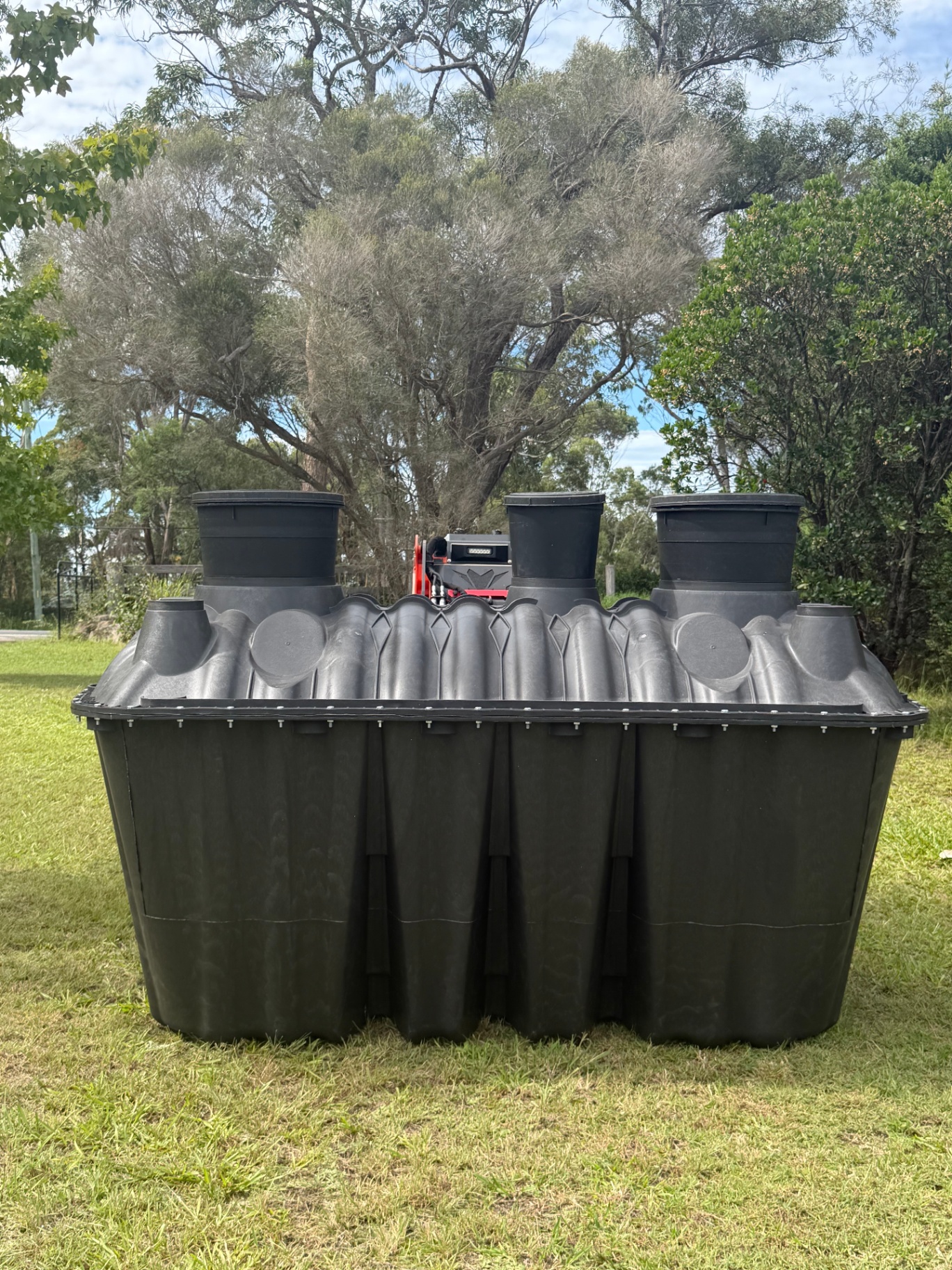 Front-on view of the Bush Billabongs 1500L three-chamber septic tank on grass with eucalyptus trees behind